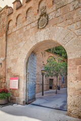 Fototapeta premium Historic Stone Archway Entrance to Montserrat Monastery. Medieval Architecture, Catalan Landmark, Sacred Site, European Travel Destination, a detailed coat of arms above the portal