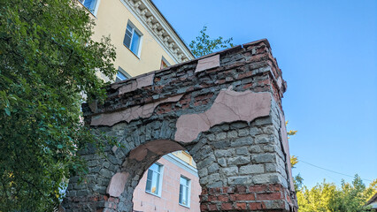 Decaying brick archway showing exposed mortar and bricks with residential building visible in...