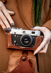 Front view of a vintage camera. In a woman's hands is a SLR camera with film from the 1970s
