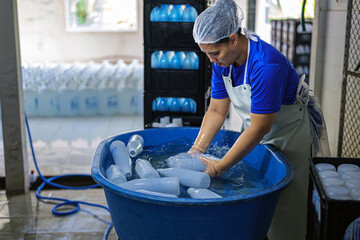 Asian fat female worker cleaning plastic water bottles outside and checking the quality of plastic...