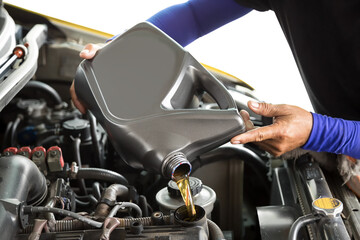 Car mechanic replacing and pouring fresh oil into engine at maintenance repair service station