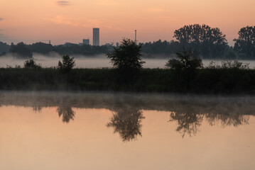 Wschód słońca nad łąką wodą, widok na kopalnię Brzeszcze, letni poranek.