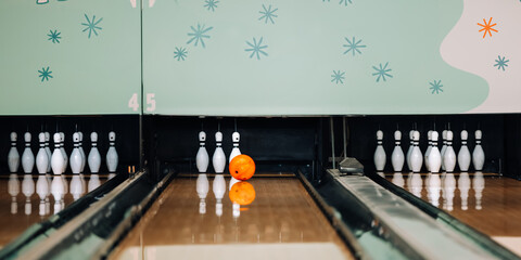 Orange bowling ball approaching last pins remaining at end of lane