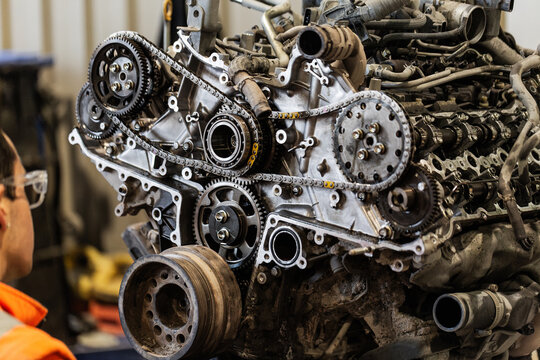 Male mechanic working on a complex engine inside industrial workshop