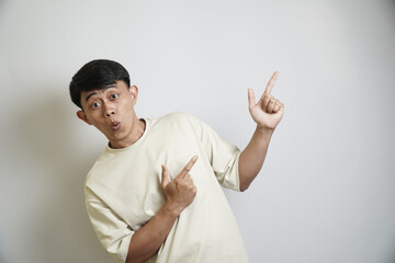Portrait of a young male with an amazed expression, gesturing to two different directions, against...
