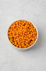 Bowl filled with sea buckthorn berries on a gray background. Top view. Concept of healthy eating, vitamins.