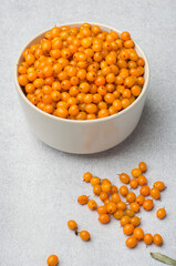 Bowl filled with sea buckthorn berries on a gray background, horizontal. Concept of healthy eating, vitamins.