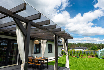 The terrace behind the house is made of beams, the roof is covered with polycarbonate.