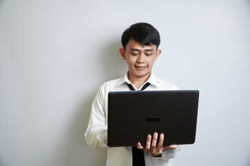 A happy male professional with a relaxed expression is looking down at a laptop and typing, appearing pleased with what he sees on the screen.