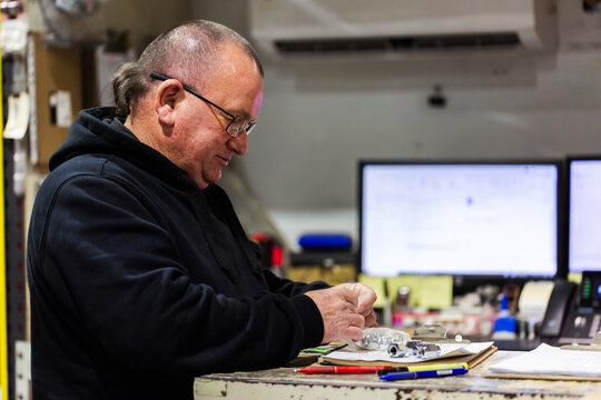 Parts man working in mechanics workshop storage room for fleet vehicle repair spare parts