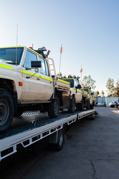 Mining fleet vehicles loaded on a flatbed truck trailer arriving at mechanics workshop for repairs