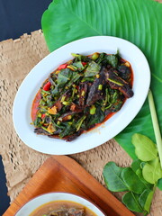 Stir-fried kale with canned fish in tomato sauce, combining fresh crunch from greens with the savory-sweet flavor of the fish, creating a simple yet delicious Thai comfort dish.