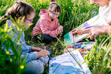 Teacher and two students with Down syndrome mixing colors and painting lupines together during an...