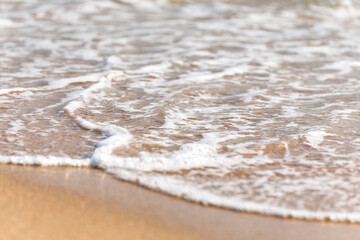 Soft wave of blue ocean on sandy beach. Blurred background.