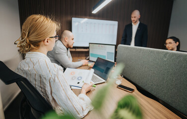 Business associates engaged in reviewing and discussing data insights in an office with modern...