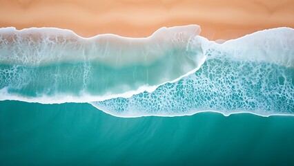 Aerial view of turquoise ocean waves gently meeting a sandy beach under soft sunlight.