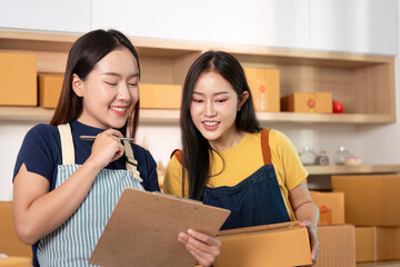 Business Collaboration. Two women reviewing project details with clipboard and boxes.