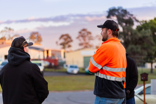 Group of workmen mechanics chatting together one man in high-vis before shift starts