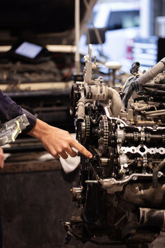 Aussie mechanics hand pointing on a partially disassembled internal combustion engine