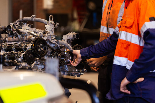 Mechanics hand holding part of vehicles internal engine inside industrial workshop