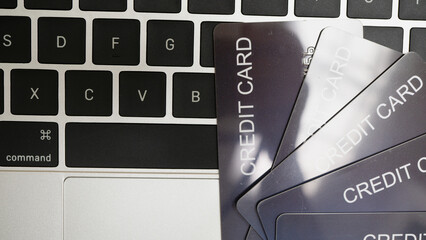 Close up image of laptop keyboard with several credit cards fanned out on top, suggesting online shopping or digital transactions