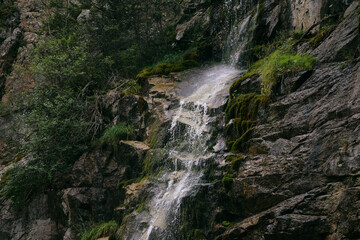a small waterfall flows down the rocks in the mountains, close-up