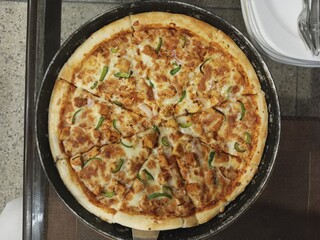 a cheesy pizza with chicken and peppers is displayed on a pan ready to be served for lunch or dinner