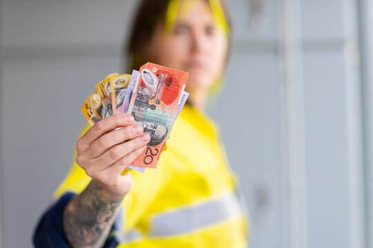 tattooed tradie holding assorted banknotes in hand