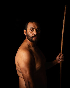 Shirtless aboriginal man holding a wooden spear