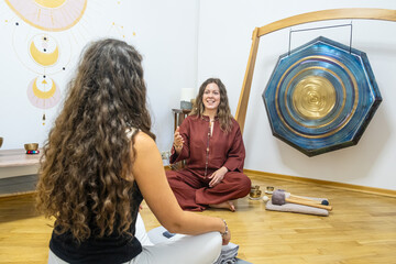 A therapist and a woman engaged in a one-on-one session using sound therapy tools, in a calm...