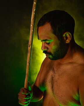 Shirtless aboriginal man holding a wooden spear