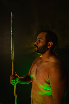 Shirtless aboriginal man holding a wooden spear