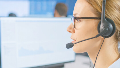 Woman working at computer wearing headset focused expression in office environment professional communication