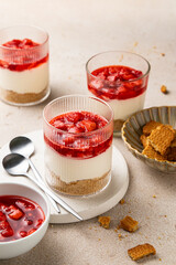 No bake individual cheesecake in glass with strawberry topping. Cheesecake cups. Summer cold parfait. Trifle with berry sauce. Home cooking. Selective focus.