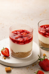 No bake individual cheesecake in glass with strawberry topping. Cheesecake cups. Summer cold parfait. Trifle with berry sauce. Home cooking. Selective focus, copy space.