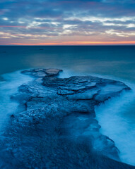 Pink horison at sunrise with the rock in the sea