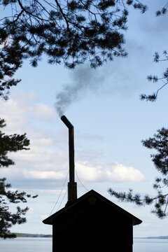 Sauna house with smoking chimney between pines, Lake Pielinen, Koli National Park, Koli, Finland