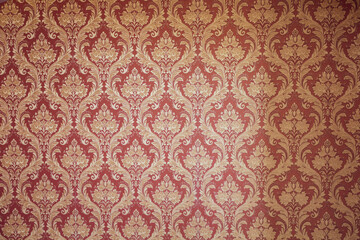 Close-up of ornate historic style damask wallpaper in gold and red tones, suitable as a decorative...