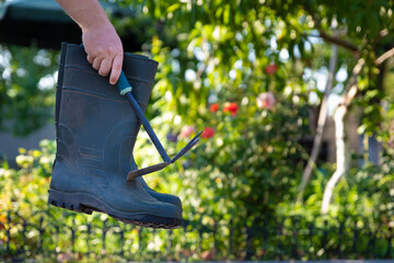 Hand Holding Garden Boot and Tool