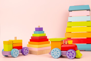 Kid toys background. Montessori wooden educational and musical toys for children. Wood train, xylophone, stacking pyramid on pink background. Front view