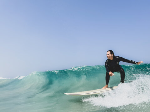 Female surfer in steamer wetsuit surfing clean green wave