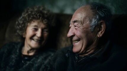 Obraz premium Elderly couple laughing together on a sofa with soft lighting and sharp focus
