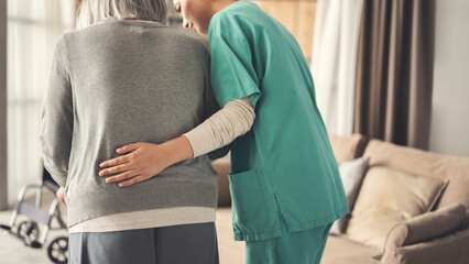 The nurse helps the elderly patient to walk