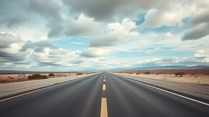 Fototapeta premium Panoramic view of an empty road under cloudy skies, capturing a serene and open landscape.