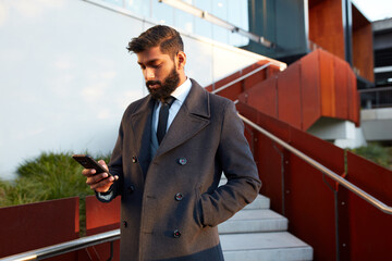 Indian architect using touchscreen device in front of building