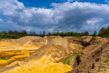 Sand quarry filled with water reflecting the cloudy sky, creating an industrial yet natural landscape