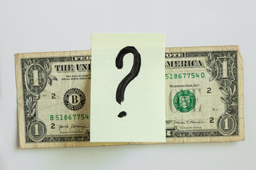 A yellow sticker with a black question mark painted on top of a one dollar bill on a white