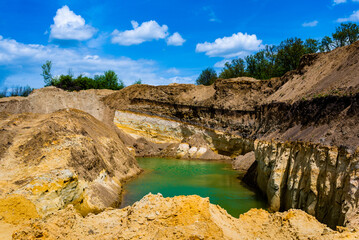 Sand quarry filled with water reflecting the cloudy sky, creating an industrial yet natural landscape