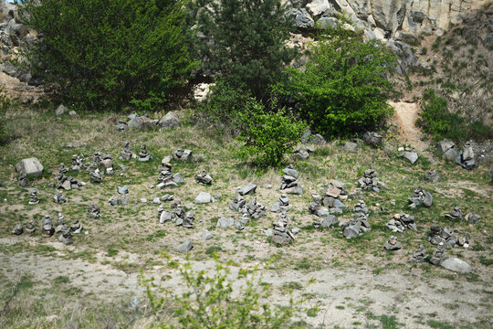 Stone cairns at Emerald Lake in Racos surrounded by green bushes and rocky cliff on a sunny day