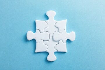 Obraz premium Four white puzzle pieces forming a square on a light blue background